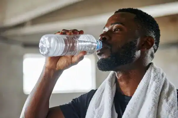 Image of man drinking water to improve hydration Bicester after work out.
